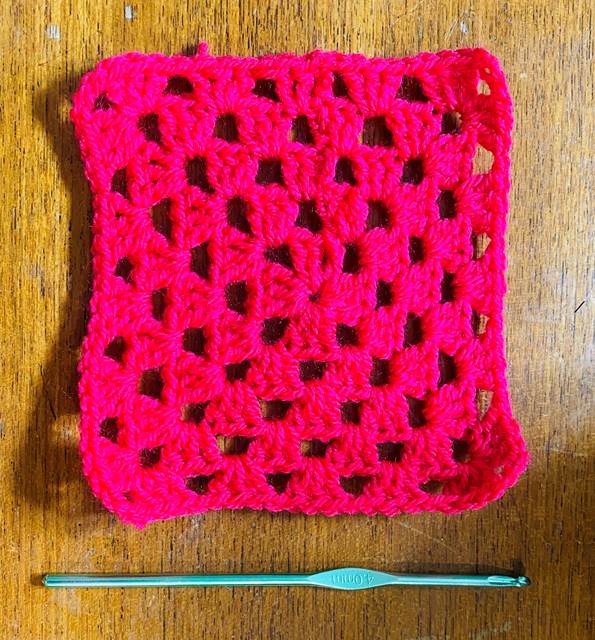 5 inch crochet granny square next to a crochet hook